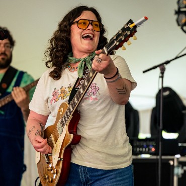 Mattie Schell singing and playing a gold-top electric guitar on stage